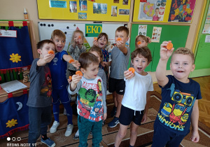 Dzieci z grupy Pszczółki stoją trzymając w ręku plasterki marchewki.